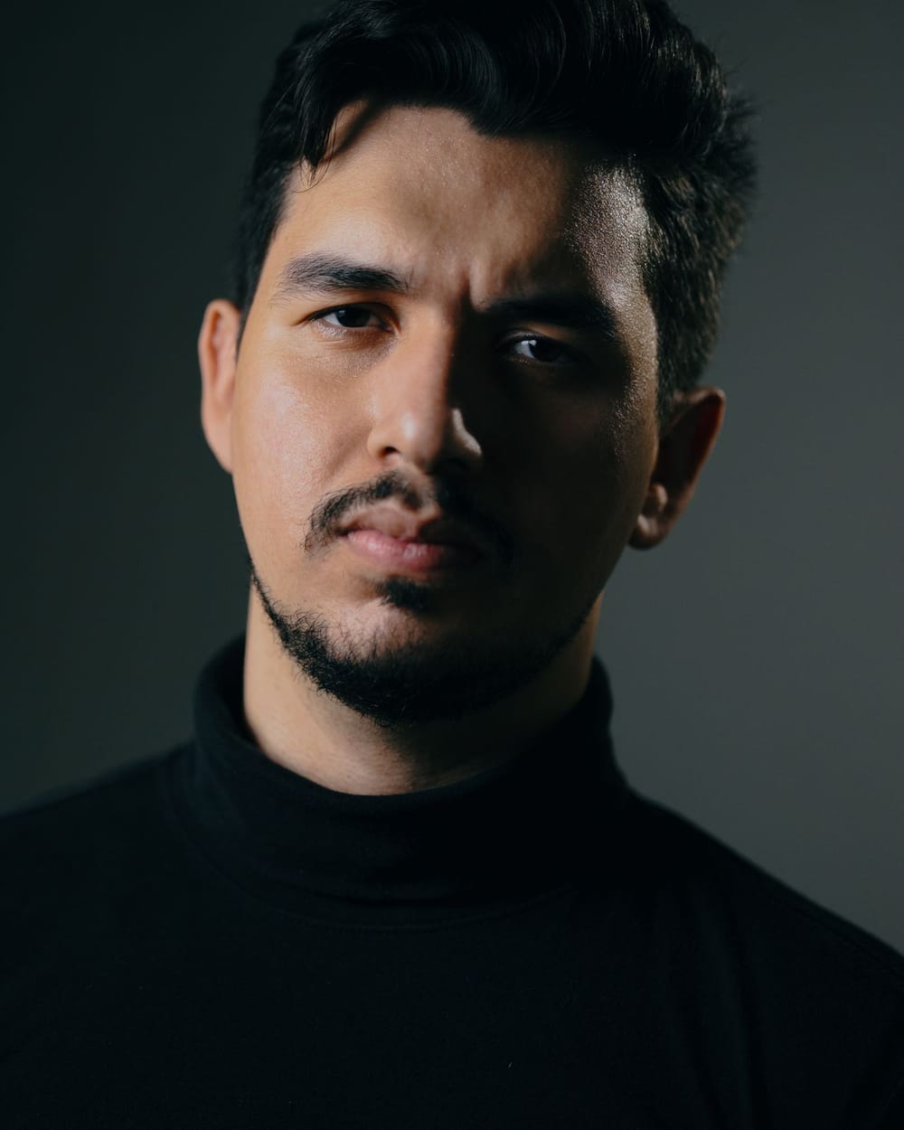 Joan Pericàs, pelo oscuro y bigote, de jersey negro, mira a cámara con luz lateral